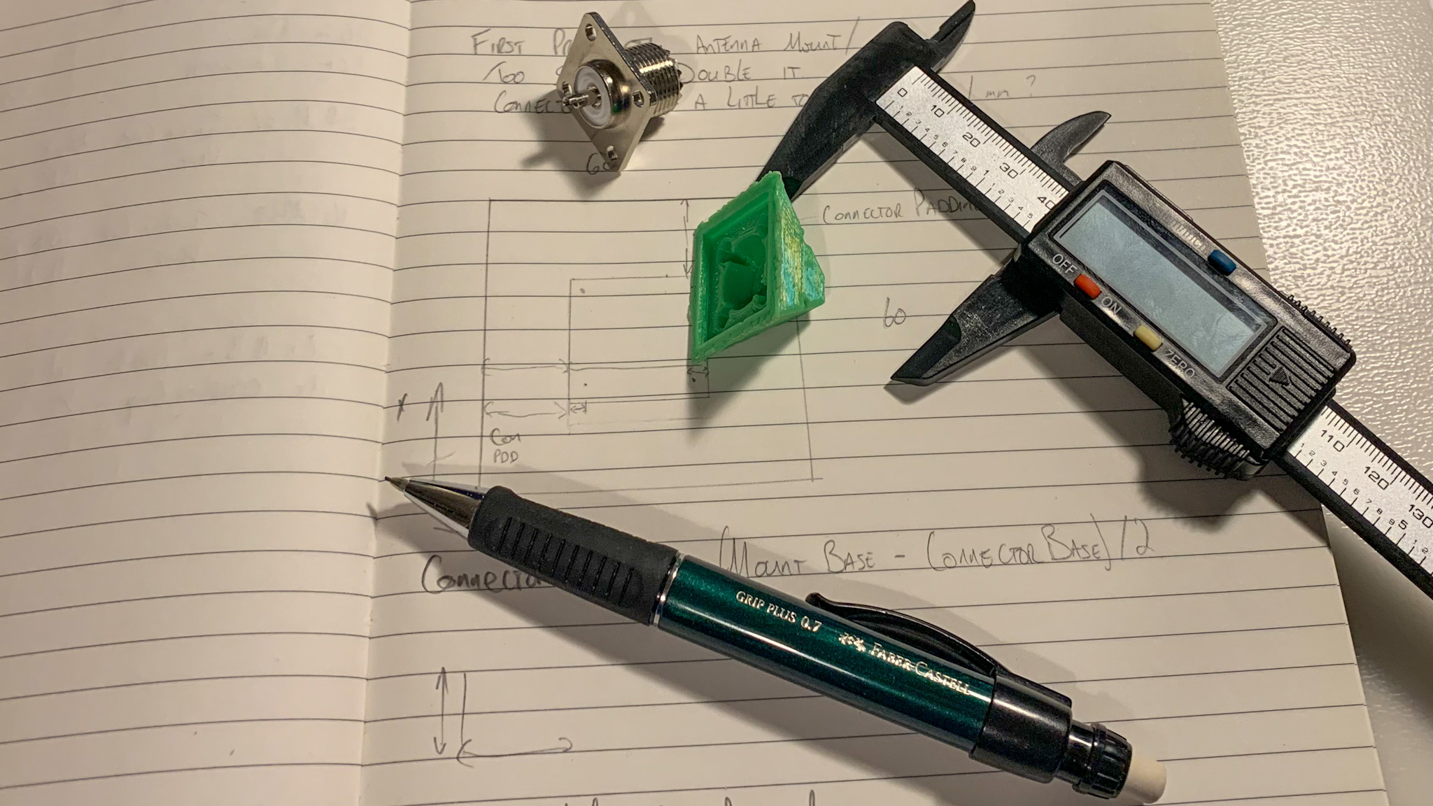 A notepad with callipers, pencil, connector and item